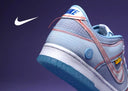 Zapatilla Nike azul claro con costuras rojas y una suela blanca.