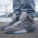 Zapatillas Air Jordan 5 de ante gris y malla con suelas translúcidas azul claro y entresuela blanca moteada.